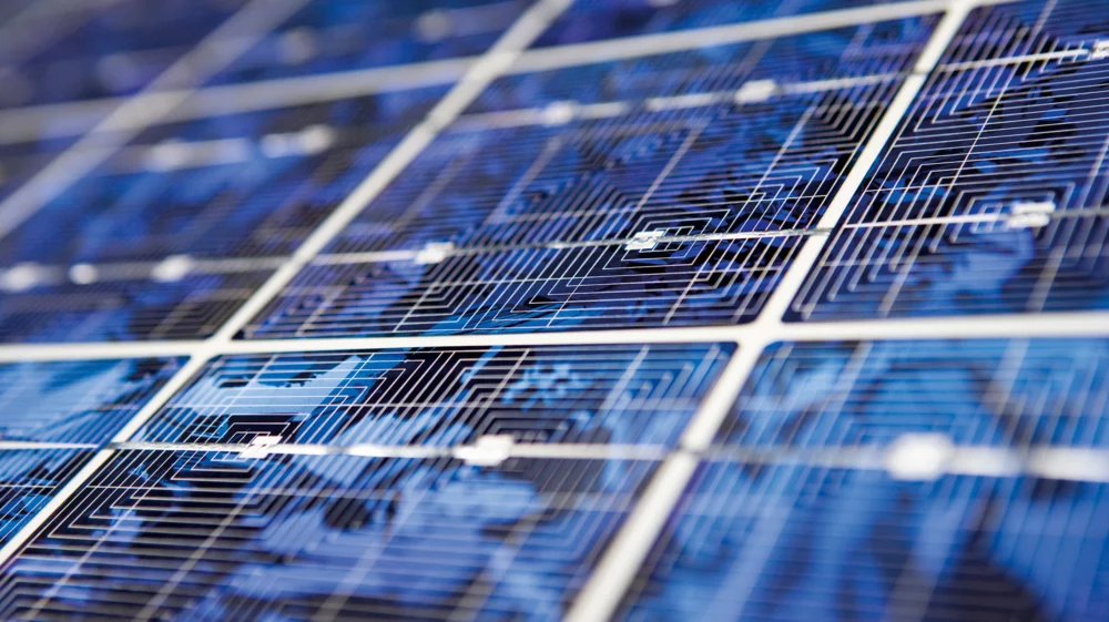 Close-up of blue photovoltaic solar panels at an angle, showing the cells' grid lines and fine wiring.