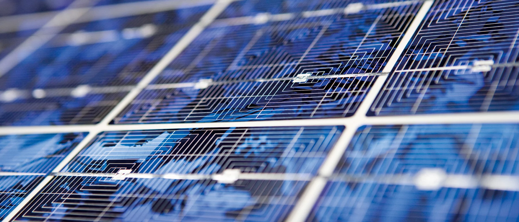 Close-up of blue photovoltaic solar panels at an angle, showing the cells' grid lines and fine wiring.