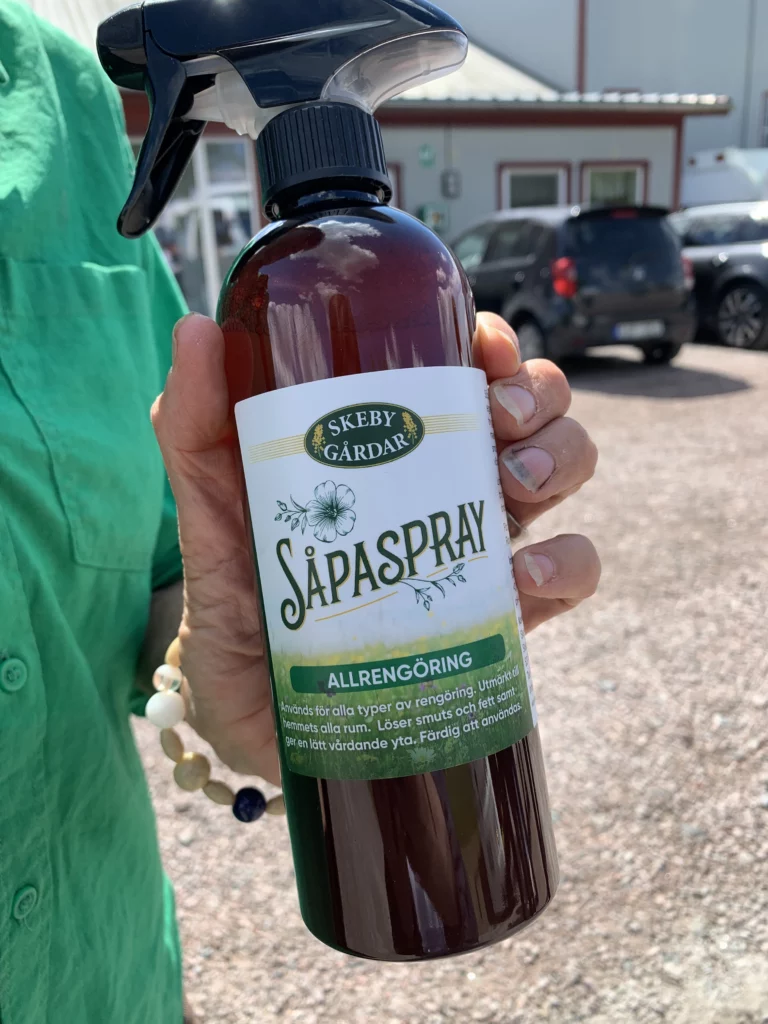 Woman holding a value added product; a cleaning spray made from rapeseed.