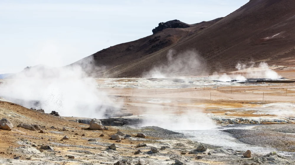 Steam rises from a geothermal field beneath a volcanic landscape