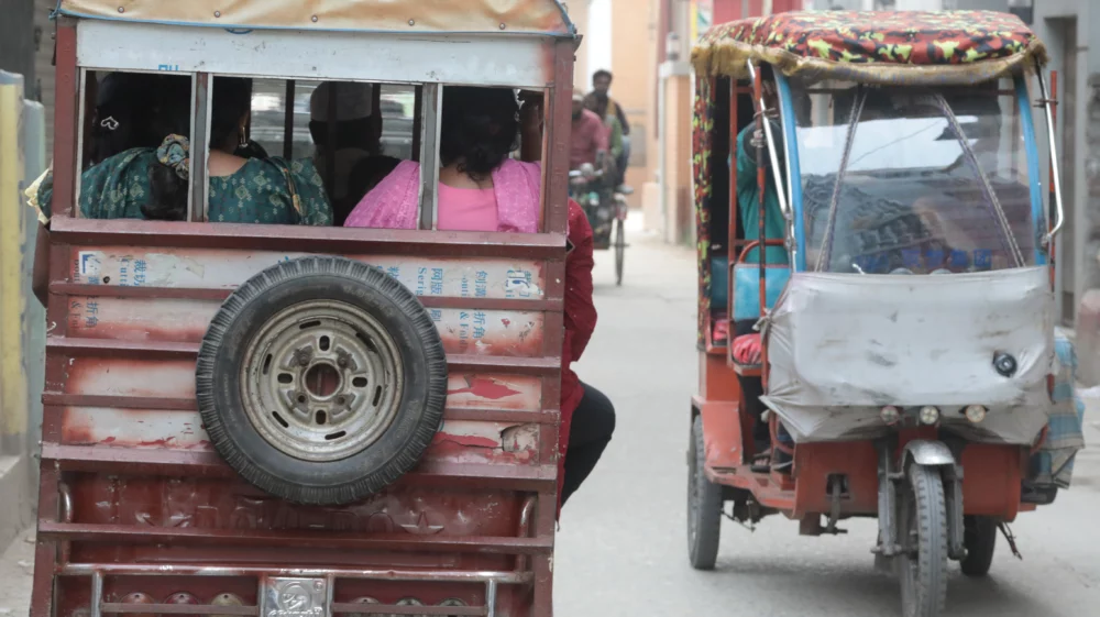 Two three-wheeled tuk tuks, one heading away from the viewer on the left and the other toward the viewer on the right.