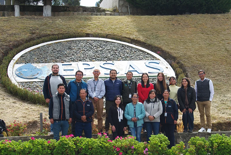 Around sixteen workshop participants and facilitators stand together in front of a large stone EPSAS sign set into a grassy bank.