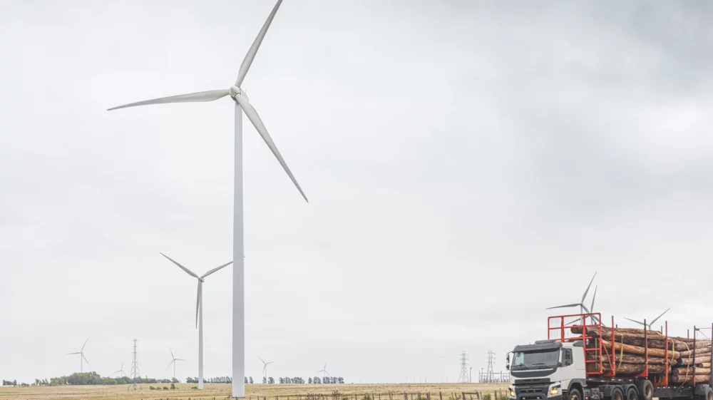 Highway crossing the countryside of Uruguay, view of the windmill fields and logging truck with eucalyptus logs.