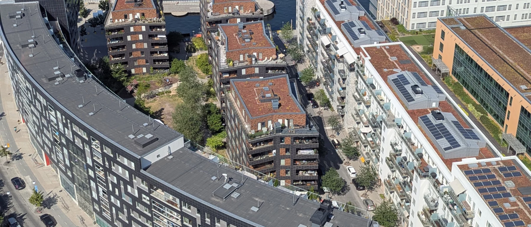Arial view of roofs of apartment buildings with solar arrays and plants on the roofs.