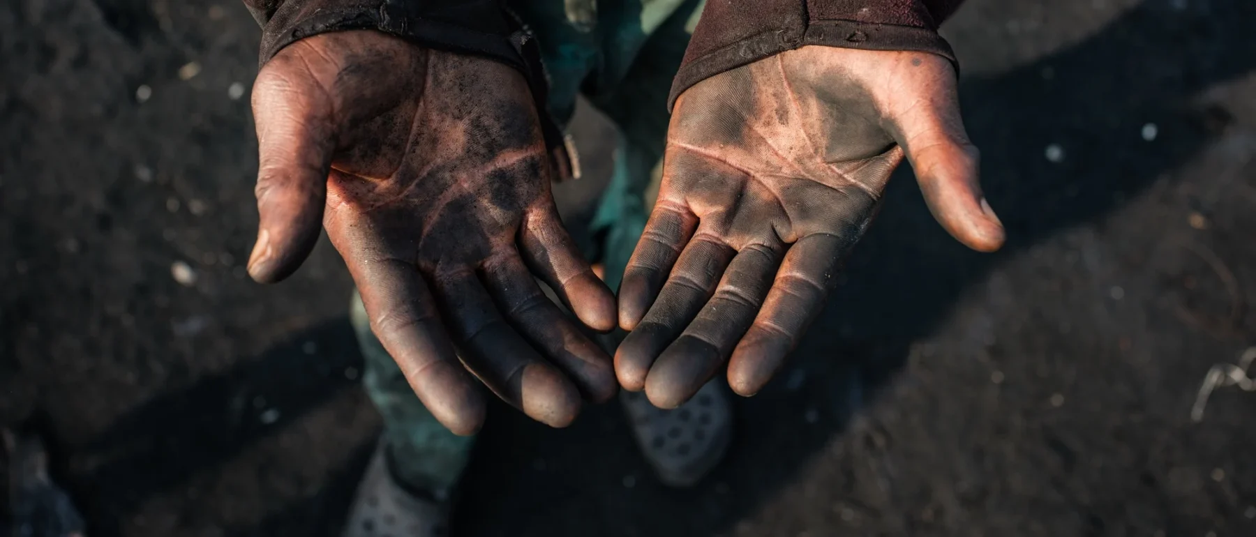 Peter Akpos's hands are covered in soot from the abattoir. Peter is a roaster who has worked for 18 years at AGIP abattoir in Port Harcourt, where cow skins are burned over open fires. Peter is exposed to thick smoke almost every day as part of his work. Despite the health risks, Peter continues this labor to support himself and his family, reflecting the daily realities of workers in the local meat processing industry. Rivers State, Nigeria. January 6 2026.