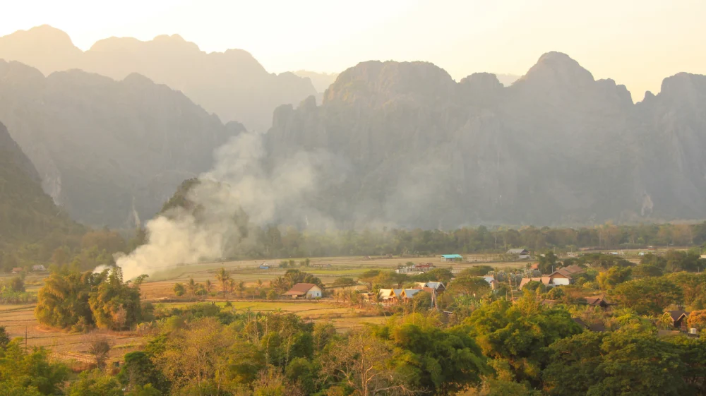 Burning Season in Vang Vieng, Laos. Landscape on a grey sky with smoke , vegetaion and hills