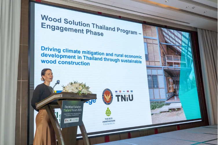 Marie Jürisoo speaks at a podium in front of a screen showing the Wood Solution Thailand Program.