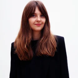 Klaudia Olmstead wears a black top with long brown hair and curtain bangs.