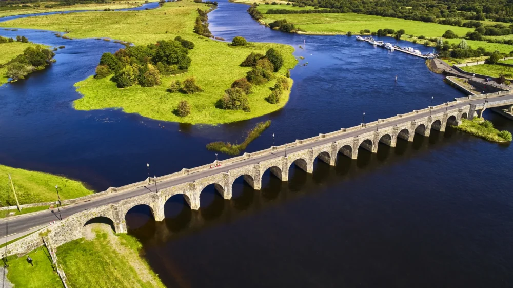 An arched bridge over the River Shannon with green countryside around it.