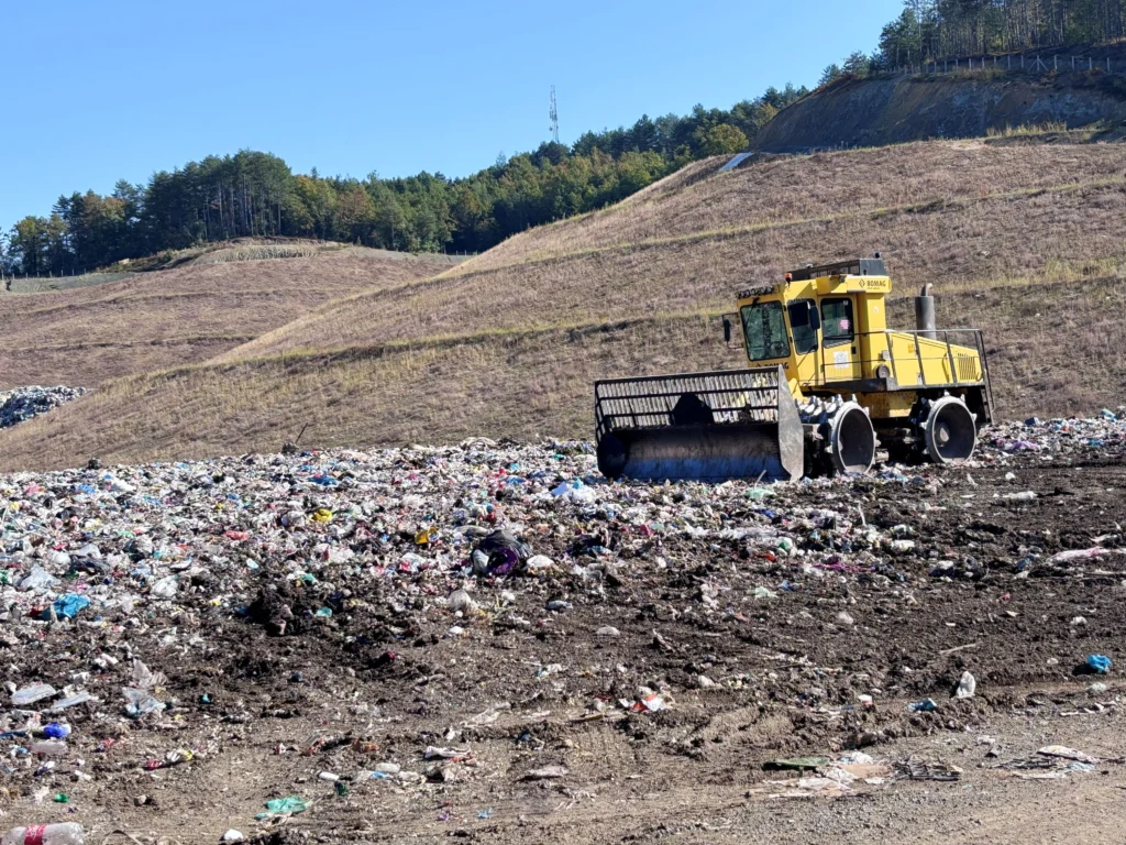 A landfill compactor spreads mixed household waste on an open landfill.
